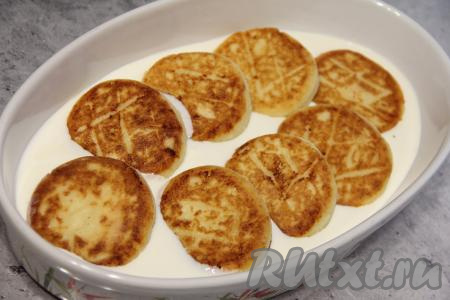 В жаропрочную форму влить сметанный соус, выложить в форму сырники.