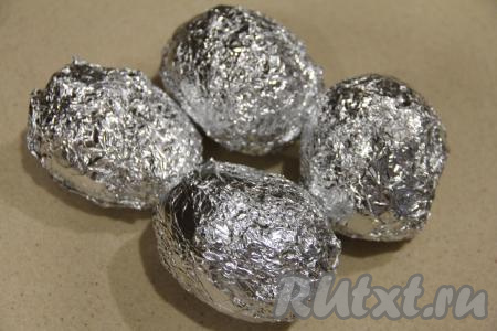 Плотно завернуть картофелину в фольгу. Аналогично смазать маслом и завернуть в фольгу все оставшиеся картошины.