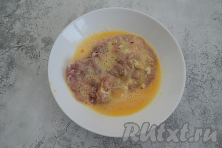 Сырое яйцо разбить в отдельную тарелку, взболтать вилкой и в полученный кляр окунуть отбивную с двух сторон.