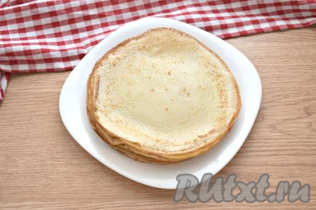 Поверхность сковороды смазываем перед выпечкой первого блина маслом (масло входит в состав теста, поэтому перед жаркой последующих блинчиков сковородку можно не смазывать, но многое зависит от качества поверхности сковороды). Очень хорошо прогреваем сковороду. Выливаем половник блинного теста на поверхность сковороды, равномерно распределяем. Жарим блинчик с двух сторон на среднем огне до румяности (примерно по минуте с каждой стороны), затем перекладываем на тарелку. Постепенно жарим все тонкие блинчики, складывая их на тарелку стопочкой. Тесто в миске периодически перемешиваем, так как оно оседает на дно. Я готовила блины на сковороде диметром 18 сантиметров, вышло 9 штук. Даём блинчикам немного остыть.