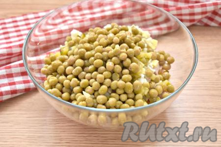 Зелёный консервированный горошек сначала откидываем на сито (или на дуршлаг), чтобы слить жидкость, а затем перекладываем в салатник.