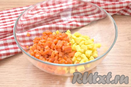 Заранее для салата отвариваем в кожуре картошку и морковь (варим с момента закипания воды минут 20-25). Яйца отвариваем после начала кипения воды в течение минут 10. Варёные картошку, морковь и яйца остужаем под холодной водой, а непосредственно перед приготовлением салата очищаем. Картошку и морковку нарезаем на небольшие кубики, перекладываем в салатник. Ингредиенты в этом салате нужно нарезать на кубики так, чтобы размер кубиков был примерно равен размеру консервированного горошка.