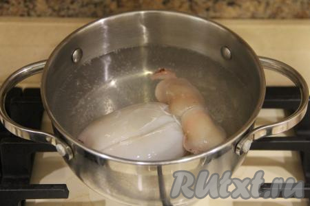 В кастрюлю влить воду, довести на сильном огне до кипения, немного уменьшить огонь. Опустить тушку кальмара в кипящую воду и варить 10 секунд на среднем огне с момента закипания. Затем достать кальмара, переложить на тарелку. Снова довести в кастрюле воду до кипения, выложить вторую тушку кальмара и тоже варить с момента закипания 10 секунд на среднем огне, после этого сразу достать из кастрюли и переложить на тарелку.