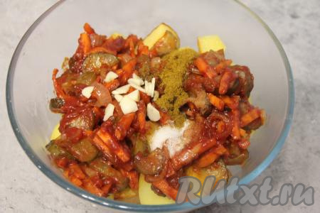 В миску с индейкой и овощами выложить обжаренный картофель, добавить нарезанный чеснок, соль и специи, перемешать.