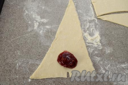 Теперь сформируем наши рогалики с начинкой, для этого возле надреза с узкой стороны треугольника нужно выложить 1 чайную ложку варенья, смешанного с крахмалом. 