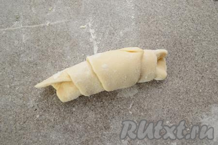 И, начиная со стороны с закрытой начинкой, свернуть тесто в рулетик. Получится рогалик из слоёного теста с вареньем. Таким образом сформировать все заготовки слоёных рогаликов.