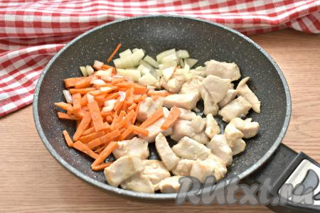 Разогреваем в сковороде растительное масло, выкладываем кусочки куриного мяса и обжариваем их на огне выше среднего 5-7 минут, периодически перемешивая. К обжаренным кусочкам курицы добавляем достаточно мелко нарезанный лук, сразу выкладываем морковку, нарезанную на брусочки.