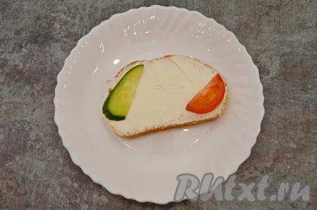 Выложить на каждый бутерброд с творожным сыром по кусочку огурца и помидора с разных сторон бутерброда. Аналогично сформировать оставшиеся бутерброды.