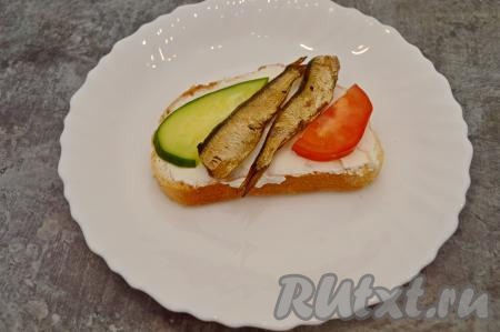 Выложить в центр бутерброда по две шпротинки. Немного подсолить овощи.