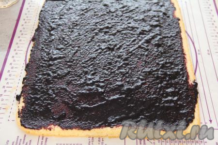 Полностью остывший корж смазать вареньем (или джемом, или ягодным конфи). Я смазала черничным вареньем.