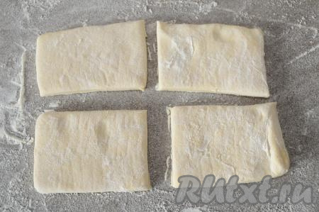 На присыпанную мукой поверхность выложить размороженный пласт слоёного теста, разделить его ножом на 4 равные части.
