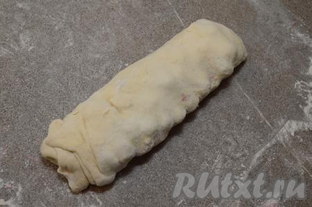 Начиная с длинного края, свернуть слоёное тесто в рулет, хорошо прижимая край теста.