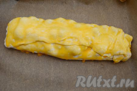 Аккуратно переложить рулет на противень, застеленный пергаментом. Смазать верх рулета взбитым яичным желтком.
