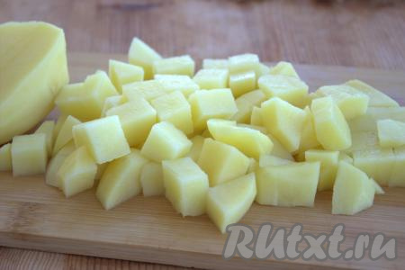 Тем временем картофель вымыть, очистить, нарезать на средние кубики. В кастрюлю с обжаренными овощами добавить картошку, перемешать.