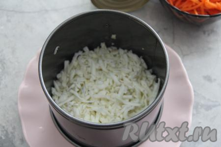 Кулинарное кольцо (я взяла кольцо диаметром 16 сантиметров) выставить на плоскую тарелку. Разделить варёные яйца на желтки и белки. Белки, натёртые на крупной тёрке, равномерно выложить в кулинарно кольцо - это будет первый слой салата. Посолить немного белки.