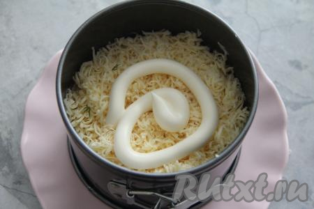 Следующим слоем равномерно разложить натёртый на мелкой тёрке сыр, смазать майонезом.