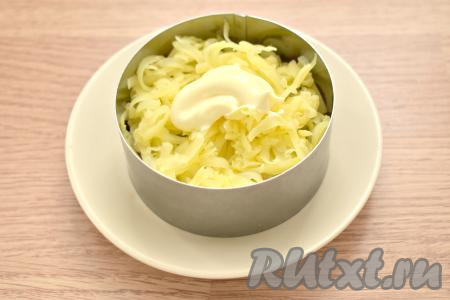 Поверх сельди равномерно раскладываем натёртый на крупной тёрке картофель, смазываем его майонезом.