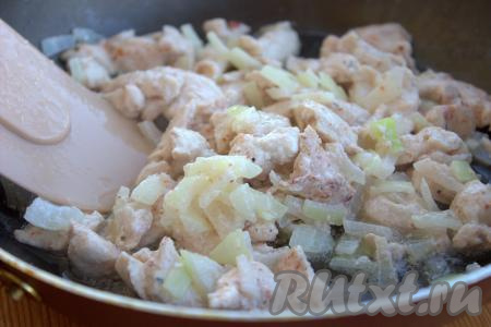 В сковороде слегка прогреть растительное масло, затем выложить кусочки куриного мяса с луком и обжаривать их на среднем огне, иногда помешивая, 3-4 минуты. Затем мясо, обжаренное с луком переложить в миску.