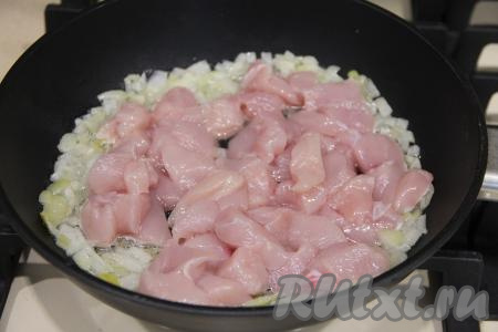 Прогреть растительное масло в сковороде, выложить мелко нарезанный лук и обжарить его минуты 2-3 (до прозрачности), помешивая, на среднем огне. После этого добавить в сковороду кусочки курицы.