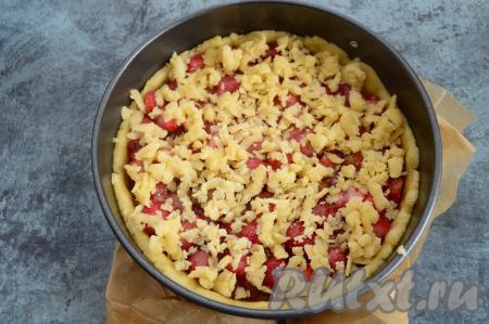 Достать из морозилки кусочек песочного теста, натереть его на тёрке (оно достаточно подмёрзло и легко натирается). Присыпать натёртым тестом клубничную начинку. Отправить подготовленный клубничный пирог с песочной основой в разогретую до 180 градусов духовку на 40-60 минут.