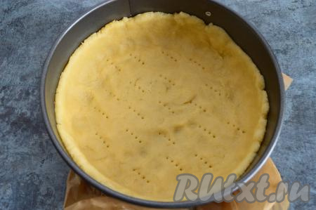 По прошествии 20 минут достать тесто из холодильника. Разъёмную форму для выпечки (я взяла форму диаметром 18 сантиметров) застелить пергаментом, смазать бока сливочным маслом. Аккуратно распределить тесто по дну формы, формирую высокий бортик. Если у вас будет форма большего диаметра, тогда бортик будет небольшой. Наколоть тесто вилкой.