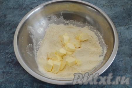 Смешать сухие ингредиенты в миске и добавить к ним сливочное масло из холодильника, нарезанное на кусочки.