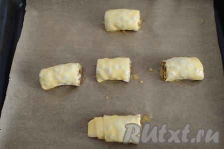 Яйцо взбить вилкой до однородной массы. Смазать взбитым яйцом наши заготовки булочек и отправить их в предварительно разогретую духовку. Слойки с изюмом выпекать минут 25 (до золотистости слоёного теста) при температуре 180 градусов. При выпечке небольшая часть сахара может вытечь - это нормально.