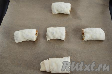 На противень, застеленный пергаментом, выложить заготовки слоек с изюмом, располагая их на расстоянии друг от друга.