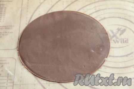 Разделить тесто на 8-9 частей. Каждую часть теста раскатать на пергаменте, слегка присыпанном мукой, в тонкий пласт, с помощью тарелки вырезать круг диаметром 18 сантиметров. Из остатков теста раскатать и вырезать ещё 1 круглый корж диаметром 18 сантиметров, а оставшееся тесто тоже раскатать, оно пойдёт для обсыпки готового медовика.