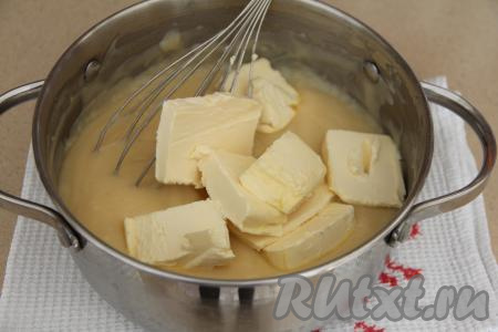 В горячий крем выложить кусочки мягкого сливочного масла и перемешать до растворения масла. Накрыть крем пищевой плёнкой так, чтобы плёнка прилегала к поверхности крема (благодаря тому, что плёнка будет лежать на поверхности крема, на нём не будет образовываться корочка в процессе остывания) и оставить до полного остывания, а затем убрать в холодильник на 5-10 часов.