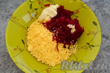 Натереть свеклу на крупной (или средней) тёрке, выложить в глубокую тарелку, добавить размятые желтки, пропущенный через пресс зубчик чеснока и 2 столовых ложки майонеза.