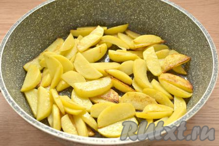 Вливаем на сковороду растительное масло, хорошо его прогреваем. Выкладываем на сковороду дольки картофеля. На среднем огне жарим картошку без крышки 10 минут, иногда перемешивая.