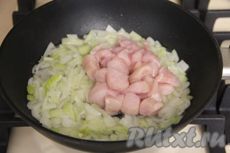 В сковороду влить растительное масло, немного прогреть его и выложить мелко нарезанный лук, обжарить его на среднем огне, помешивая, до золотистого цвета (на это потребуется минут 5). Затем добавить кубики куриного филе, перемешать.