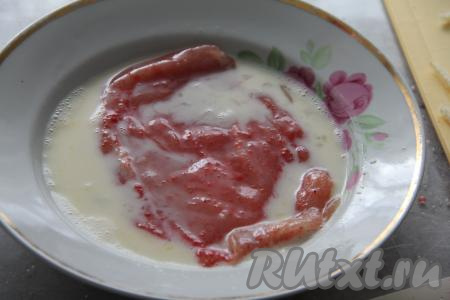 В миске соединить сырое яйцо и молоко, взбить вилкой до однородности. Обмакнуть каждое куриное филе в яично-молочный кляр со всех сторон.