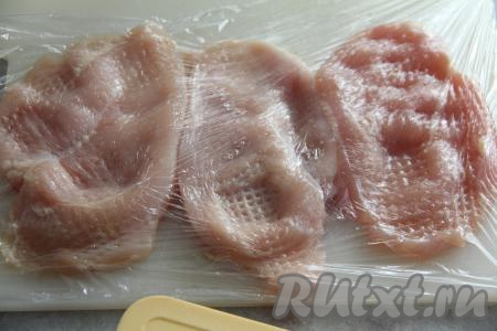 Куриное филе выложить на разделочную доску, накрыть пищёвой плёнкой и отбить с двух сторон кулинарным молотком.