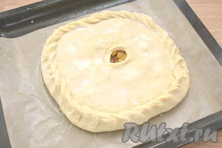 Раскатываем вторую часть теста. Накрываем им начинку. Скрепляем края, а в центре делаем отверстие для выхода пара. Поверхность пирога смазываем молоком.