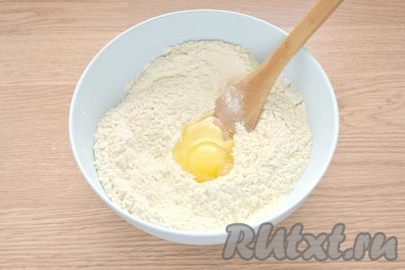 В центр мучной смеси разбиваем яйцо. Перемешиваем его с мукой ложкой.
