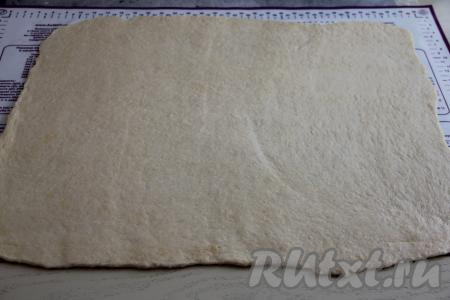 Тесто округлится и поднимется, увеличившись в объёме в 2-3 раза. Обмять тесто, выложить на поверхность, присыпанную мукой, а затем раскатать его в прямоугольный пласт, толщина которого должна быть примерно 2-3 миллиметра.