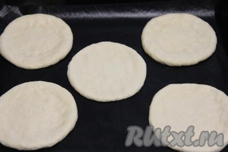 Каждую часть теста размять руками в не тонкую лепёшку и выложить на противень, застеленный ковриком (или пергаментом) для выпечки. Выкладывать лепёшки нужно на небольшом расстоянии друг от друга.