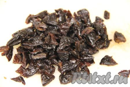 Чернослив обдать кипятком, обсушить и нарезать на кусочки (мелко нарезать не нужно). Добавить чернослив к нарезанным коржам и грецким орехам.