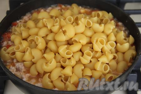 Всыпать сухие макароны в сковороду, влить 500 миллилитров горячей воды, перемешать, довести до кипения, уменьшить огонь до минимума.