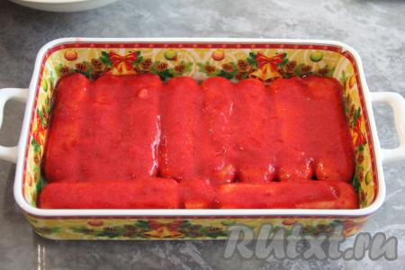 Форму для формирования тирамису лучше брать с бортиками (у меня - керамическая форма размером 18х27 сантиметров). Печенье "Савоярди" обмакнуть в клубничное пюре и выложить в форму в один слой (я выложила 10 печенюшек). Часть пюре выложить поверх печенья.