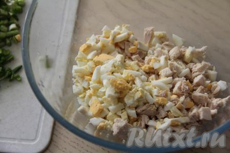 Куриное мясо (у меня - филе) отварить до готовности (в течение минут 25-30 после закипания воды), после этого остудить и нарезать на мелкие кубики. 3 яйца предварительно сварить вкрутую (на отваривание с момента закипания воды потребуется минут 9-10), затем остудить их, почистить и нарезать на мелкие кубики. Соединить в миске нарезанные яйца и куриное мясо.