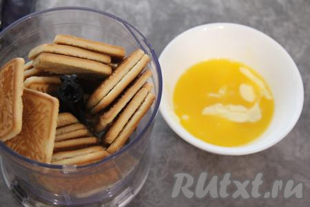 Для начала приготовим основу чизкейка, для этого нужно печенье измельчить в мелкую крошку. Я измельчила печенье в измельчителе, если его нет, можно поместить печенье в целлофановый пакет и прокатать поверх пакета скалкой до измельчения печенюшек в мелкую крошку. Сливочное масло растопить.