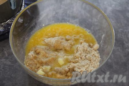 В миске соединить крошку из печенья и растопленное масло, тщательно перемешать ложкой. В форму для выпечки диаметром 18 сантиметров (я для формирования этого десерта взяла разъёмное кулинарное кольцо нужного диаметра, его дно сформировала из фольги, сложенной в 2 слоя), выложить получившуюся смесь из печенья и масла, формируя основу чизкейка с достаточно высокими бортиками, утрамбовать. На время, пока будем готовить творожную основу, поставить форму с основой чизкейка в холодильник.&nbsp;