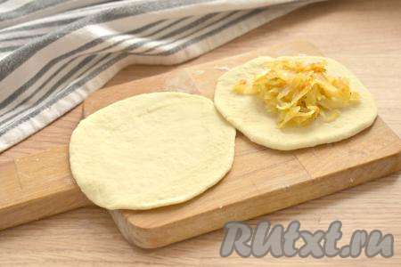 Каждый кусочек теста на присыпанной мукой поверхности раскатываем в лепёшку диаметром 12-13 сантиметров. В центр каждой лепёшки кладём полную столовую ложку с горкой капустной начинки.