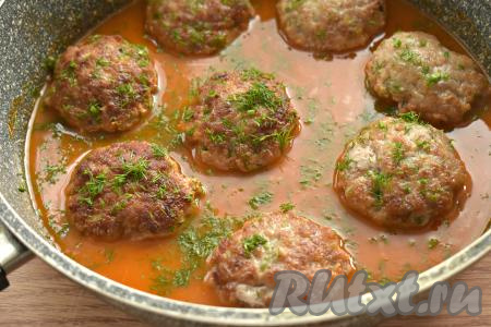 Даём томатной подливе закипеть, накрываем сковороду крышкой и тушим котлеты на минимальном огне 10 минут (за это время 1 раз котлетки можно перевернуть, чтобы они пропитались подливой со всех сторон). Готовые котлетки снимаем с огня, посыпаем, по желанию, измельчённым укропом (или другой зеленью).