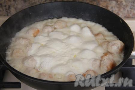 Влить закипевший сметанный соус к обжаренным фрикаделькам, перемешать, дать закипеть, а после этого убавить огонь до минимума. Томить фрикадельки в течение 10 минут под крышкой. За это время фрикадельки можно несколько раз перемешать, обволакивая их соусом со всех сторон.