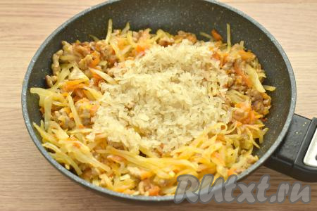 Рис промываем водой, лишней жидкости даём стечь. После того как капуста с фаршем обжарятся 8-10 минут, добавляем в сковороду рис, перемешиваем, готовим 5 минут.