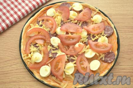 Помидор нарезаем на тонкие ломтики, раскладываем их на пиццу поверх начинки.